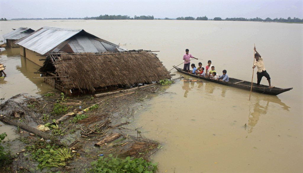 Flood-affected local residents move to safer places on a boat after heavy rains at Jajimukh village